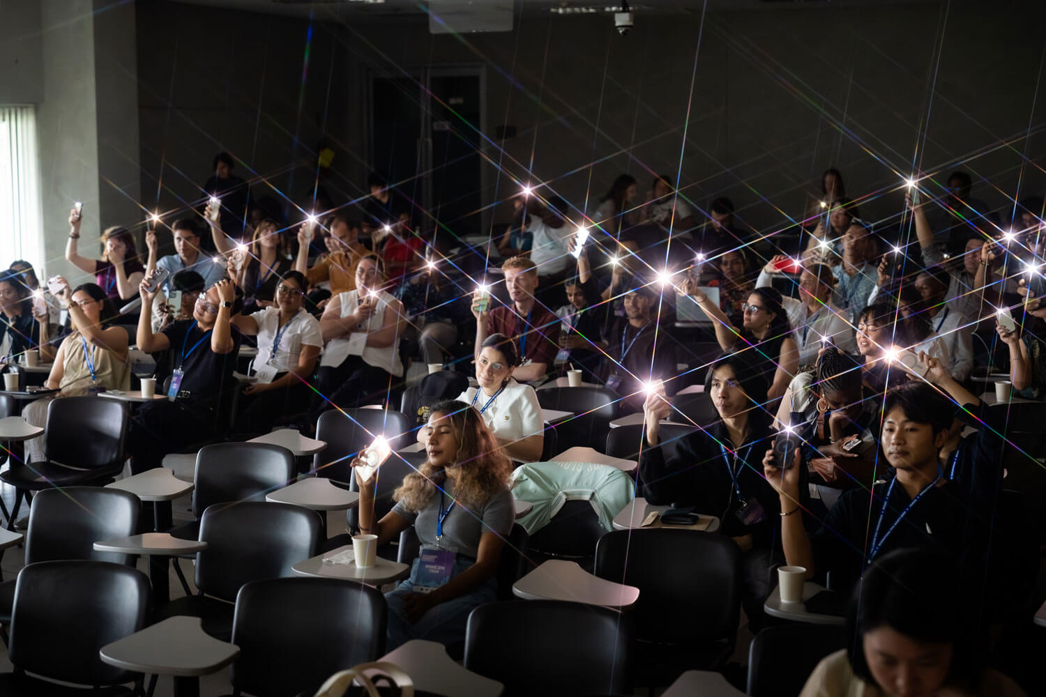 An audience holding up phone lights during an ICSW 2025 gathering in Bangkok